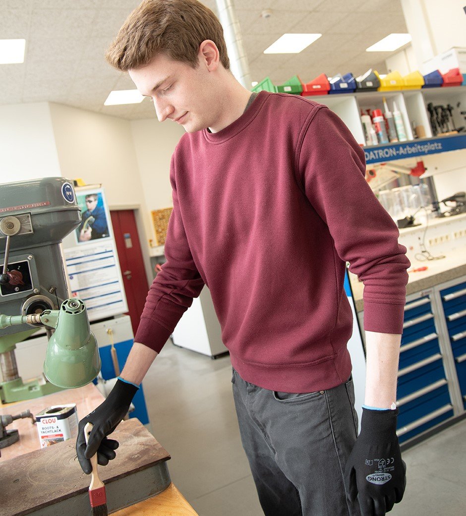 Markus Pöpper, Auszubildender am Fachbereich Elektrotechnik und Informatik, hilft beim Lackieren der neuen Schränke. (Foto: FH Münster/Katharina Kipp)