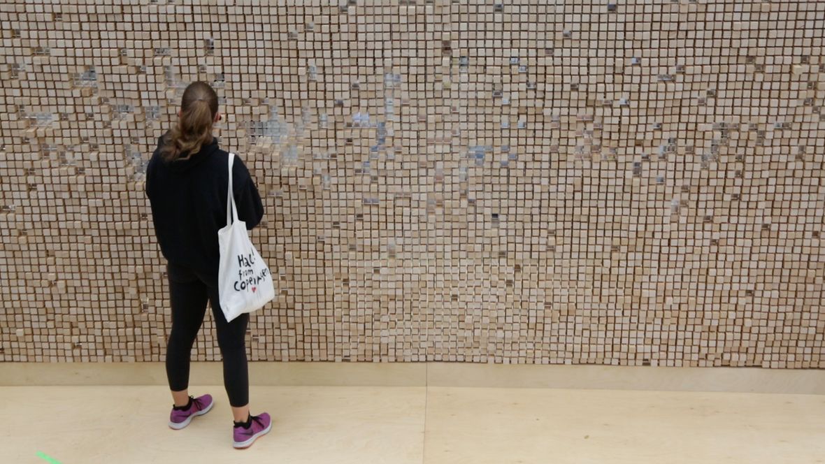 Segovia: Anfangs gleicht die Verschwindende Wand einer dichten Mauer... © Celia de Coca Die Verschwindende Wand in Segovia ...dann ziehen die ersten Besucher die Holzklötze aus der Wand ... © Celia de Coca Die Verschwindende Wand in Segovia ...entdecken die Inschriften... © Celia de Coca Die Verschwindende Wand in Segovia ...immer mehr Menschen kommen und stöbern - mit Abstand - durch die Zitate.... © Celia de Coca Die Verschwindende Wand in Segovia ... bis die Menschen auf der anderen Seite sichtbar werden © Celia de Coca