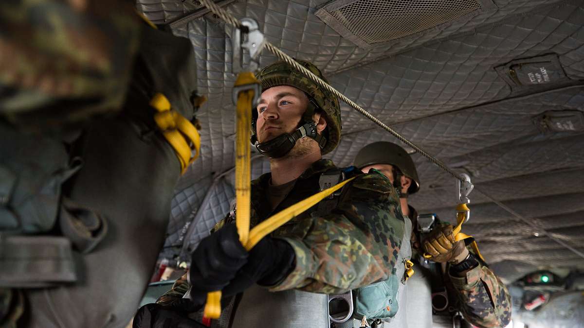 In der Absetzmaschine befestigen die Soldatinnen und Soldaten die gelben Fallschirm-Reißleinen per Karabinerhaken an einem Stahlseil. Ihre Länge ist so gewählt, dass der Schirm nach dem Absprung in ausreichender Entfernung zum Flugzeug öffnet.  Bundeswehr/Maximilian Schulz