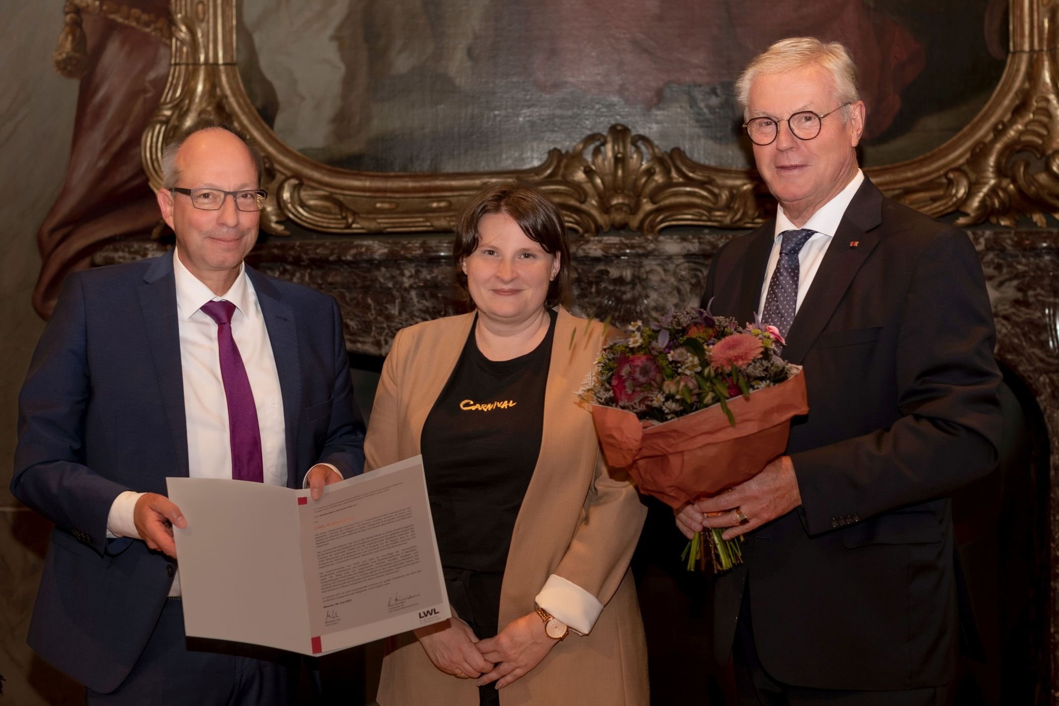 Den LWL-Kulturpreis übergeben LWL-Direktor Matthias Löb (l.), und Klaus Baumann, Vorsitzender der LWL-Landschaftsversammlung, (r.) an Frieda Wieczorek, Vorsitzende des Shademakers Carnival Club / LWL