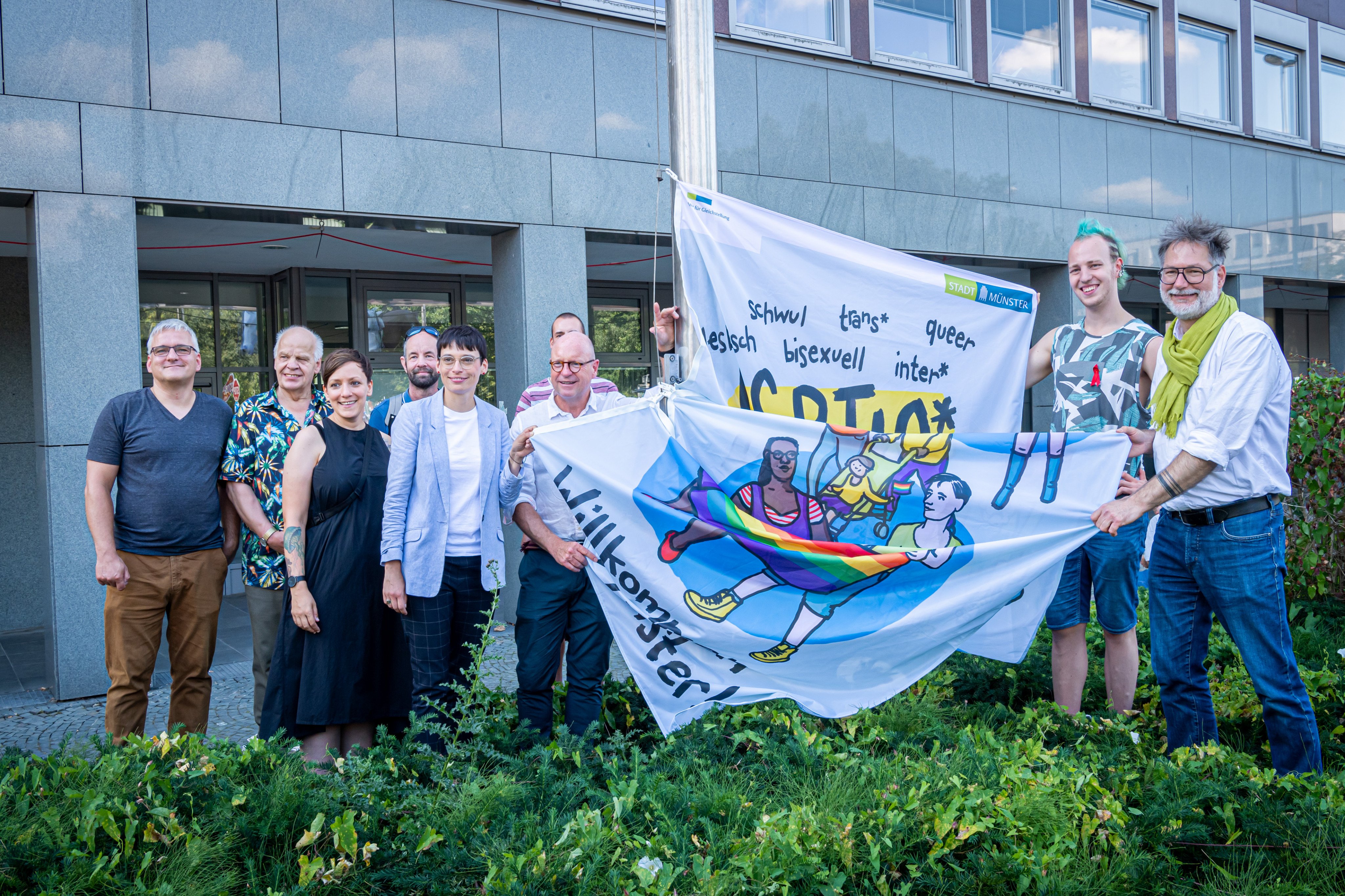 Josefine Paul, die neue Ministerin für Kinder, Jugend, Familie, Gleichstellung, Flucht und Integration des Landes Nordrhein-Westfalen und Botschafterin des CSD Münster 2022 (Zweite von links, vordere Reihe) und Oberbürgermeister Markus Lewe (Dritter von links, vordere Reihe) hissten zum Start der Pride Weeks gemeinsam die Regenbogenflagge an Stadthaus 2 (Foto: Stadt Münster. Michael C. Möller)