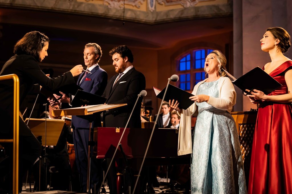 "Adventskonzert aus der Frauenkirche": Die vier Solist*innen des Abends, Diana Damrau, Nicole Chirka, Mauro Peter und Martin-Jan Nijhof stehen singend vor der Dirigentin Marie Jacquot.