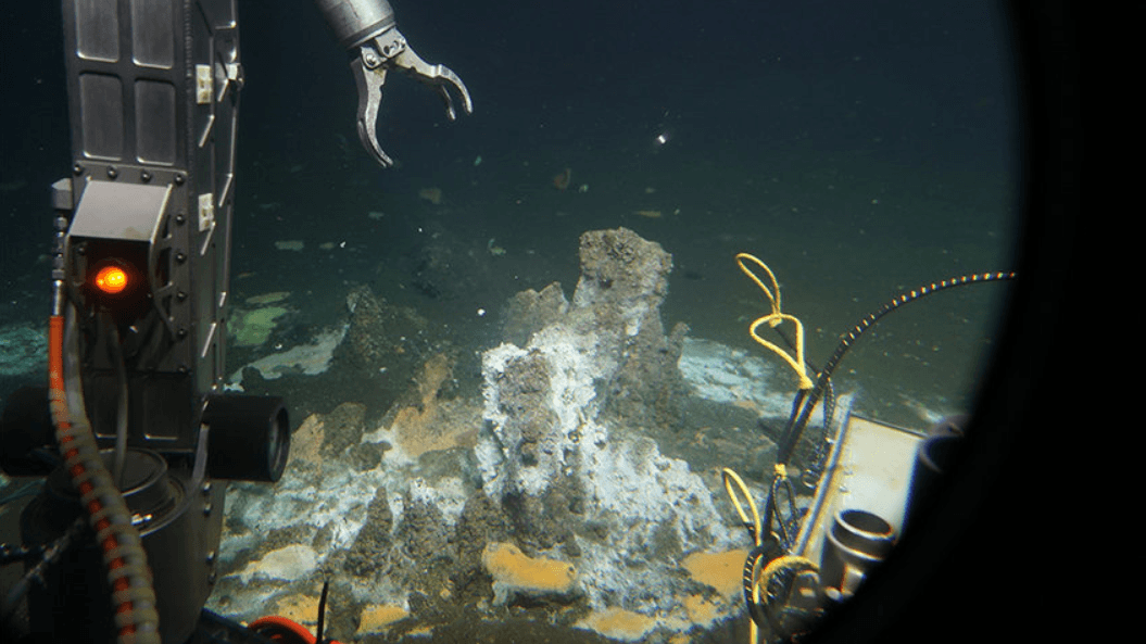 Im Scheinwerferlicht des US-amerikanischen Tiefseetauchboots ALVIN ist ein kleines rotbraunes Massiv aus… © Woods Hole Oceanographic Institution