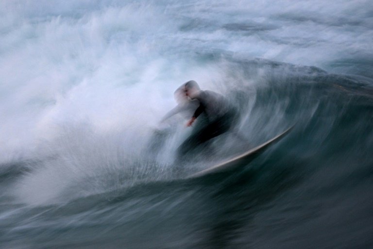 Im Licht eines seltenen blauen Supermondes vergnügt sich ein Surfer vor der Küste der australischen Metropole Sydney. Bild: Saeed KHAN / AFP